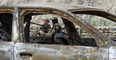 Kyrgyz soldiers are seen behind a burnt vehicle outside the village of Kok-Tash near the Kyrgyzstan-Tajikistan border in southwestern Kyrgyzstan, about 440 kilometers (275 miles) southwest of Bishkek, Kyrgyzstan, May 5, 2021. (AP File Photo)