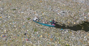 An aerial view shows men collect waste of plastic residues, glass and other materials at the Cerron Grande reservoir in Potonico, El Salvador, on Sept. 9, 2022. (AFP Photo)