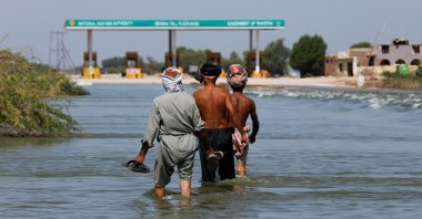 Displaced people walk on flooded highway, following rains and floods during the monsoon season in Sehwan, Pakistan, Sept. 16, 2022. (Reuters Photo)
