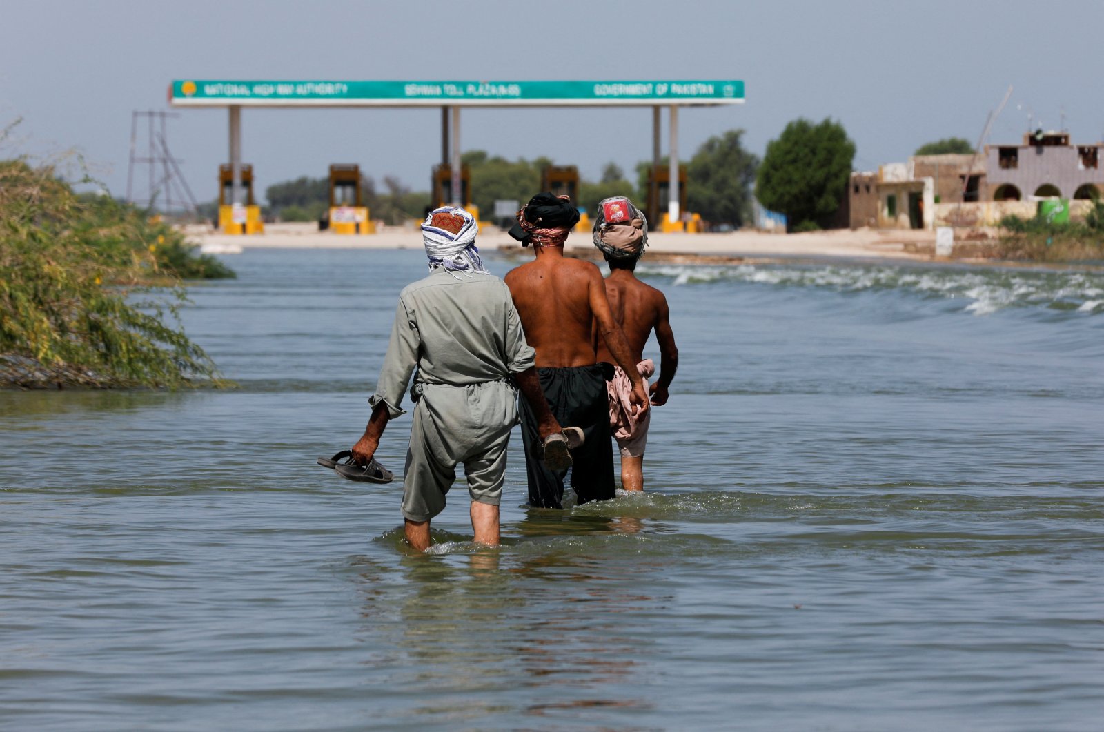 Displaced people walk on flooded highway, following rains and floods during the monsoon season in Sehwan, Pakistan, Sept. 16, 2022. (Reuters Photo)