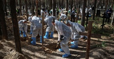 Members of the Ukrainian Emergency Service work at a place of mass burial during exhumation in the town of Izium, recently liberated by the Ukrainian Armed Forces, in the Kharkiv region, Ukraine, Sept. 19, 2022. (Reuters Photo)