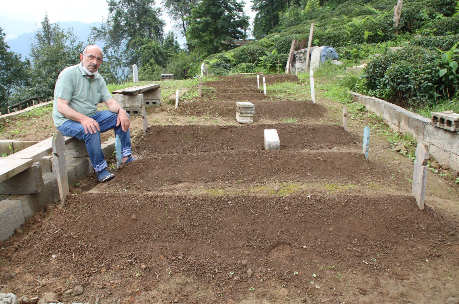 Ali Genç sits next to the graves of family members, in Rize, northern Türkiye, Aug. 31, 2021. (DHA PHOTO)
