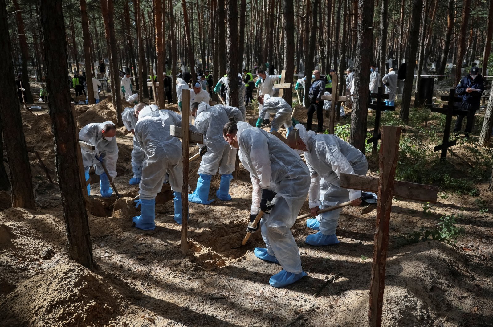 Members of the Ukrainian Emergency Service work at a place of mass burial during exhumation in the town of Izium, recently liberated by the Ukrainian Armed Forces, in the Kharkiv region, Ukraine, Sept. 19, 2022. (Reuters Photo)