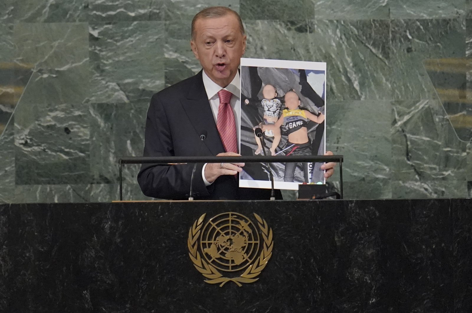 Türkiye President Recep Tayyip Erdogan holding the photo of Syrian refugee children addresses the 77th session of the United Nations General Assembly, Sept. 20, 2022 at U.N. headquarters. (AP Photo/Mary Altaffer)