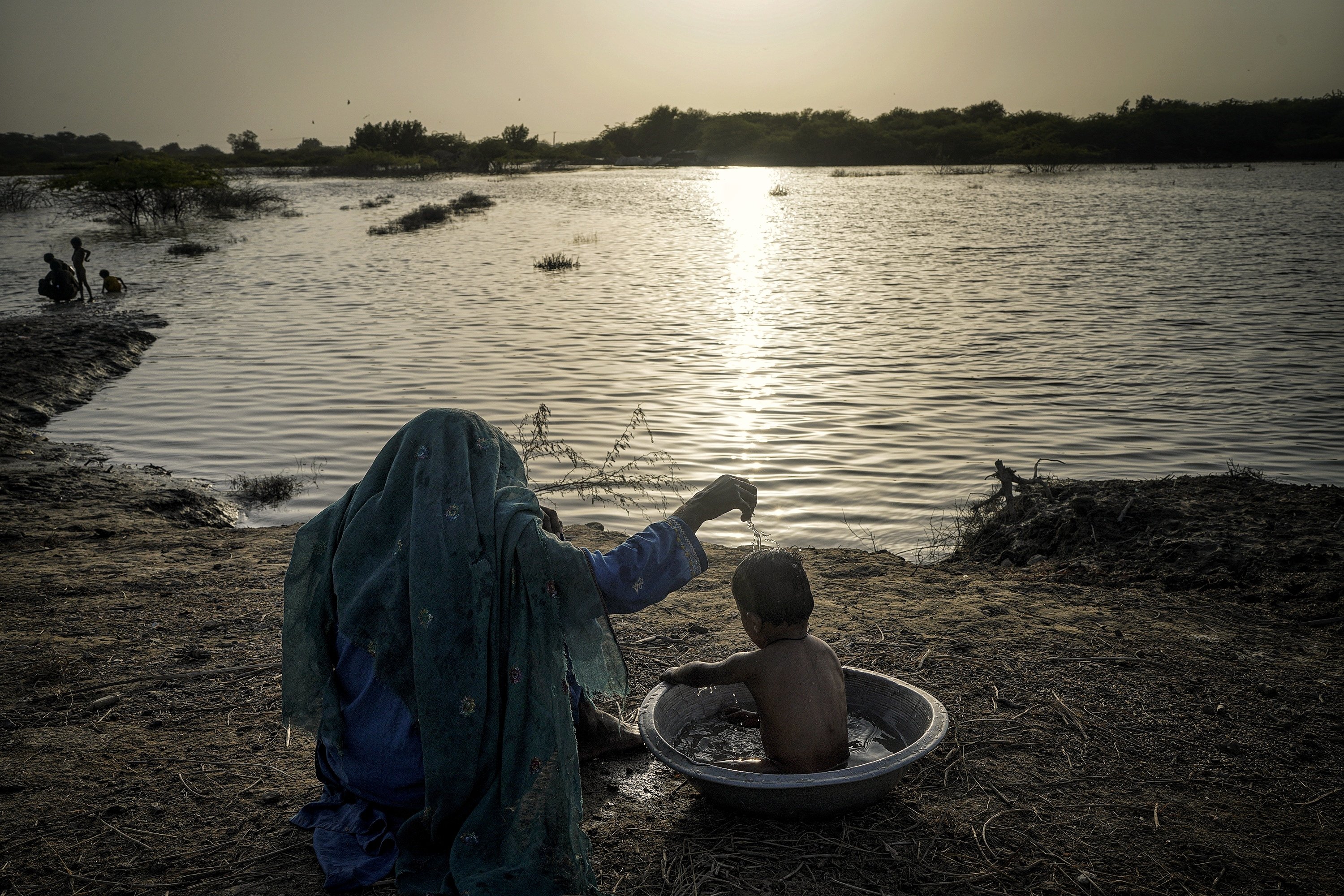 A woman washes her child by the river, in Sindh, Pakistan, Sept. 18, 2022. (PHOTO BY UĞUR YILDIRIM) 