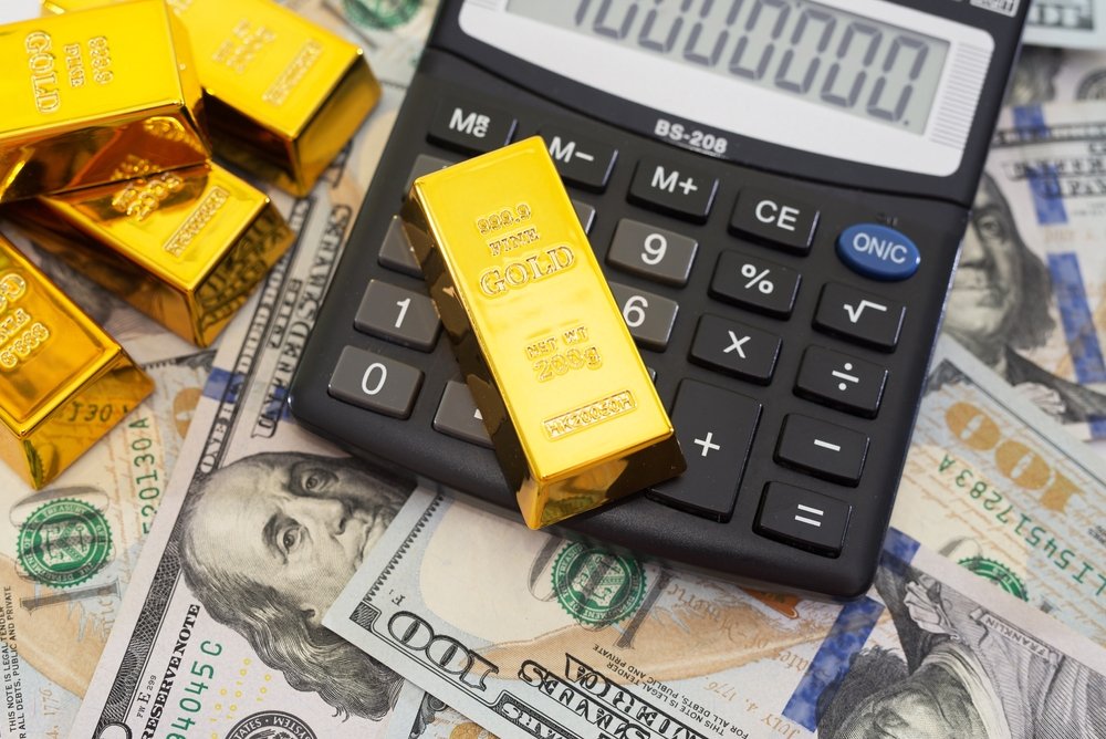 Gold bars and a calculator are seen on U.S. dollar banknotes in this undated file photo. (Shutterstock Photo)