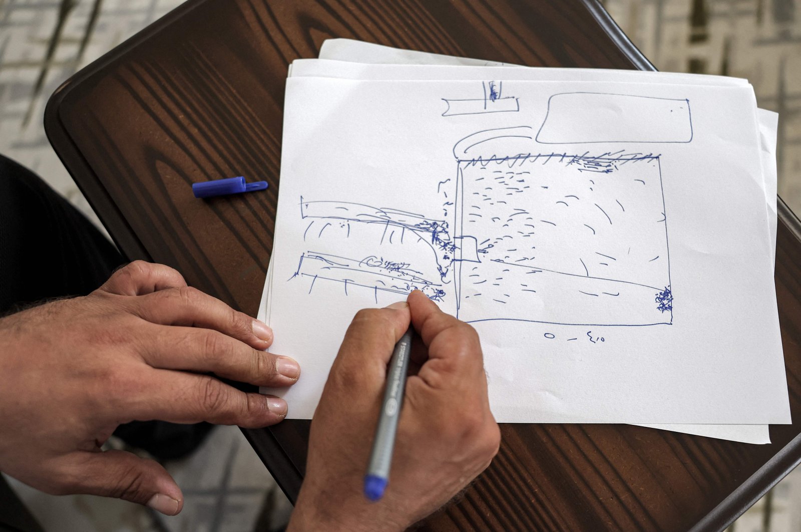 Mutassem Abd al-Sater, a 42-year-old former inmate of Sednaya prison, draws a rudimentary sketch of the prison plan during an interview at his house in Reyhanlı in Türkiye&#039;s southern Hatay province near the border with Syria, Aug. 10, 2022. (AFP Photo)