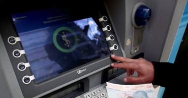 A man adds money into his account at an İşBank ATM in Istanbul, Türkiye, Sept. 20, 2022. (EPA Photo)