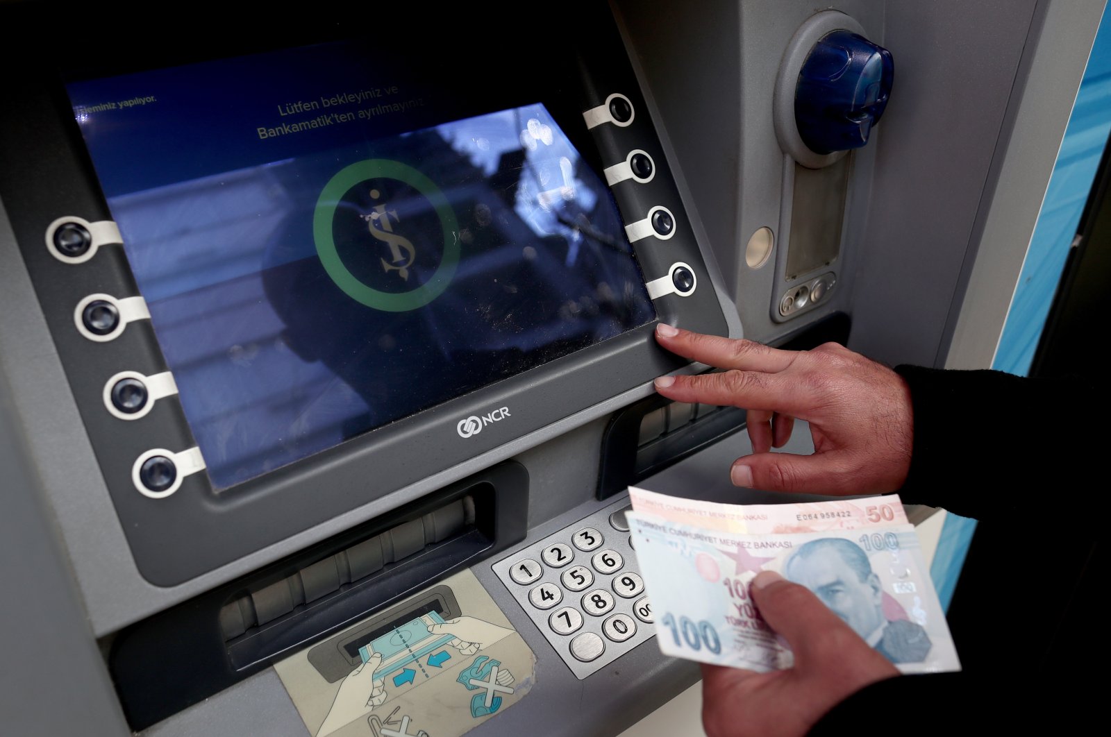 A man adds money into his account at an İşBank ATM in Istanbul, Türkiye, Sept. 20, 2022. (EPA Photo)