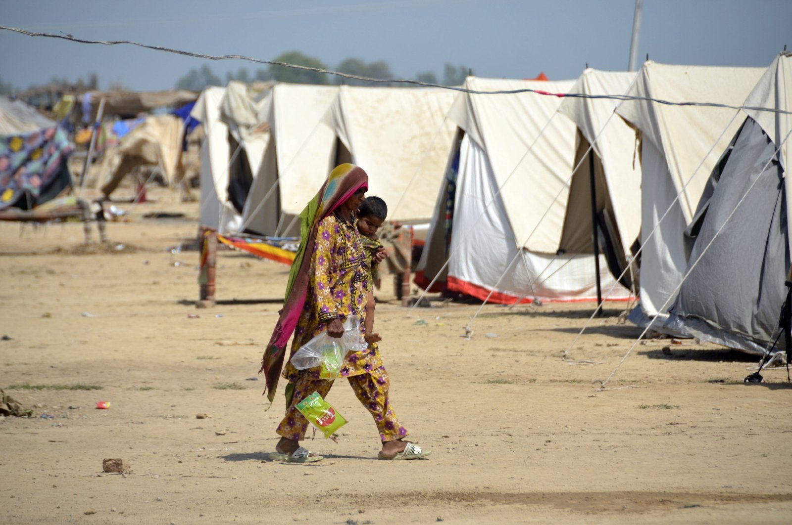 A woman walks at a camp after leaving her flood-hit home, in Jaffarabad, a district of Baluchistan province, Pakistan, Wednesday, Sept. 21, 2022. (AP)