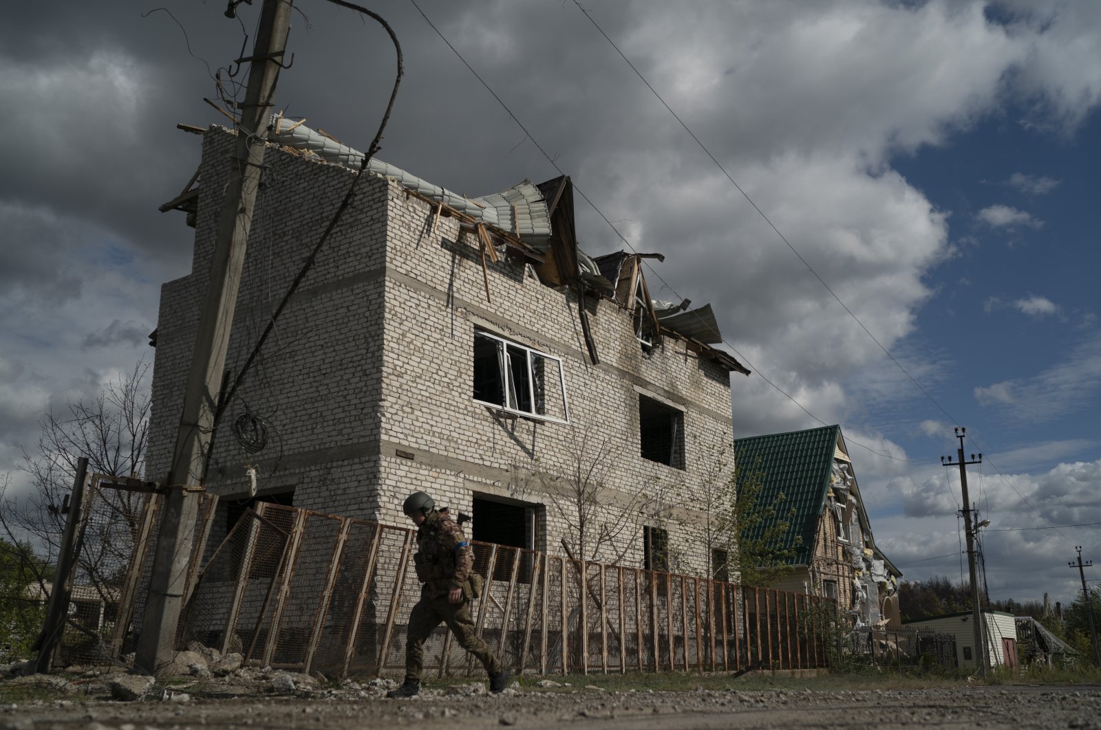 A Ukrainian serviceman from Dnipro-1 regiment walks past a damaged building in the retaken village of Shchurove, Ukraine, Sunday, Sept. 25, 2022. (AP Photo/Leo Correa)