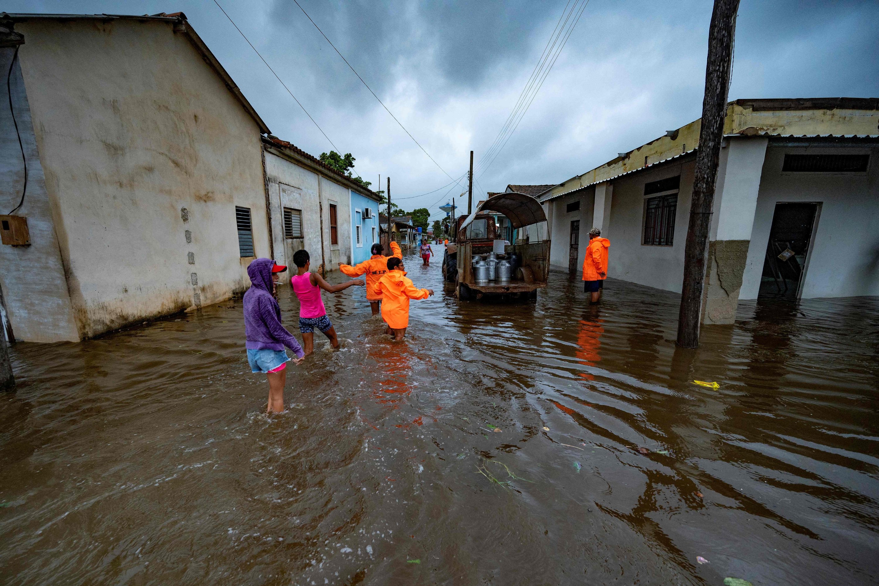 Orang-orang berjalan melalui jalan yang banjir di Batabano, Kuba, 27 September 2022. (AFP Photo)