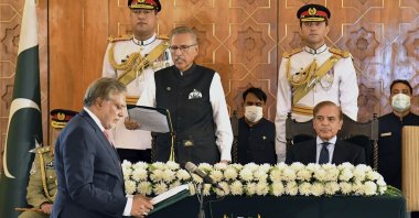Pakistan's President Arif Alvi (C) administrates the oath from newly appointed Finance Minister Ishaq Dar (L), as Prime Minister Shahbaz Sharif (R) watches during a ceremony in Islamabad, Pakistan, Sept. 28, 2022. (Press Information Department via AP)