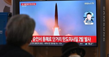 People watch a television screen showing a news broadcast with file footage of a North Korean missile test, Seoul, South Korea, Sept. 28, 2022. (AFP Photo)