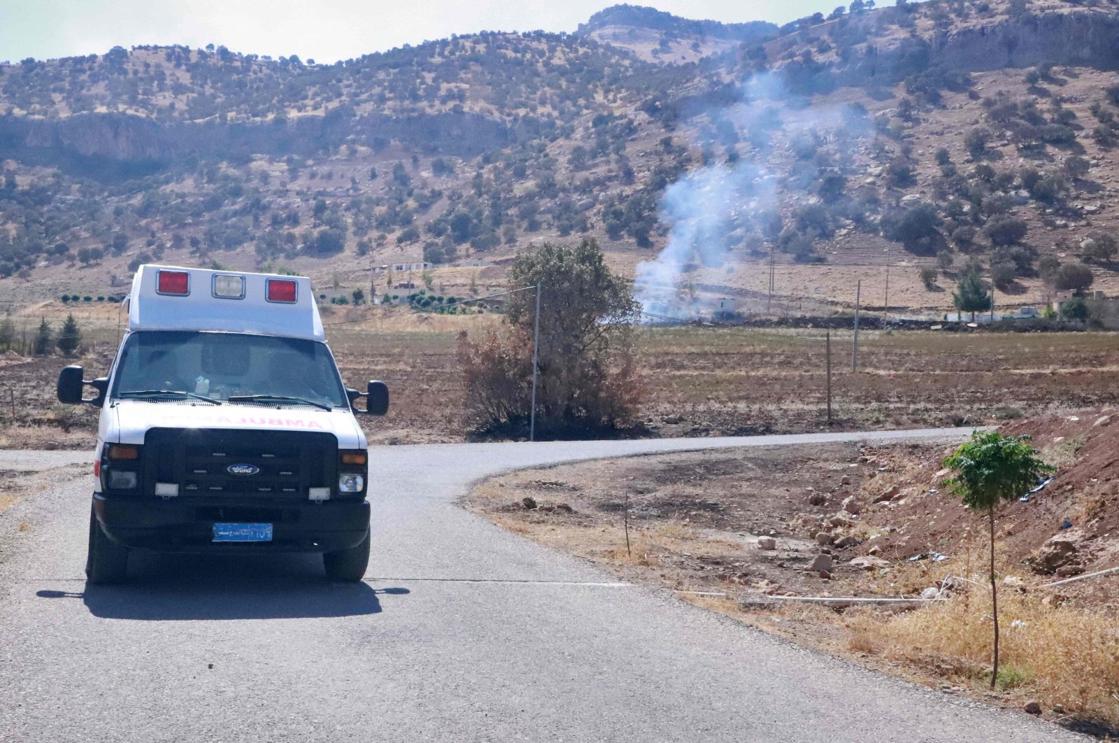 Smoke billows as an ambulance drives in the area of Zargwez, 15 kms outside the Iraqi city of Sulaimaniyah, where several exiled Iranian Kurdish parties maintain offices, on September 28, 2022. (AFP)