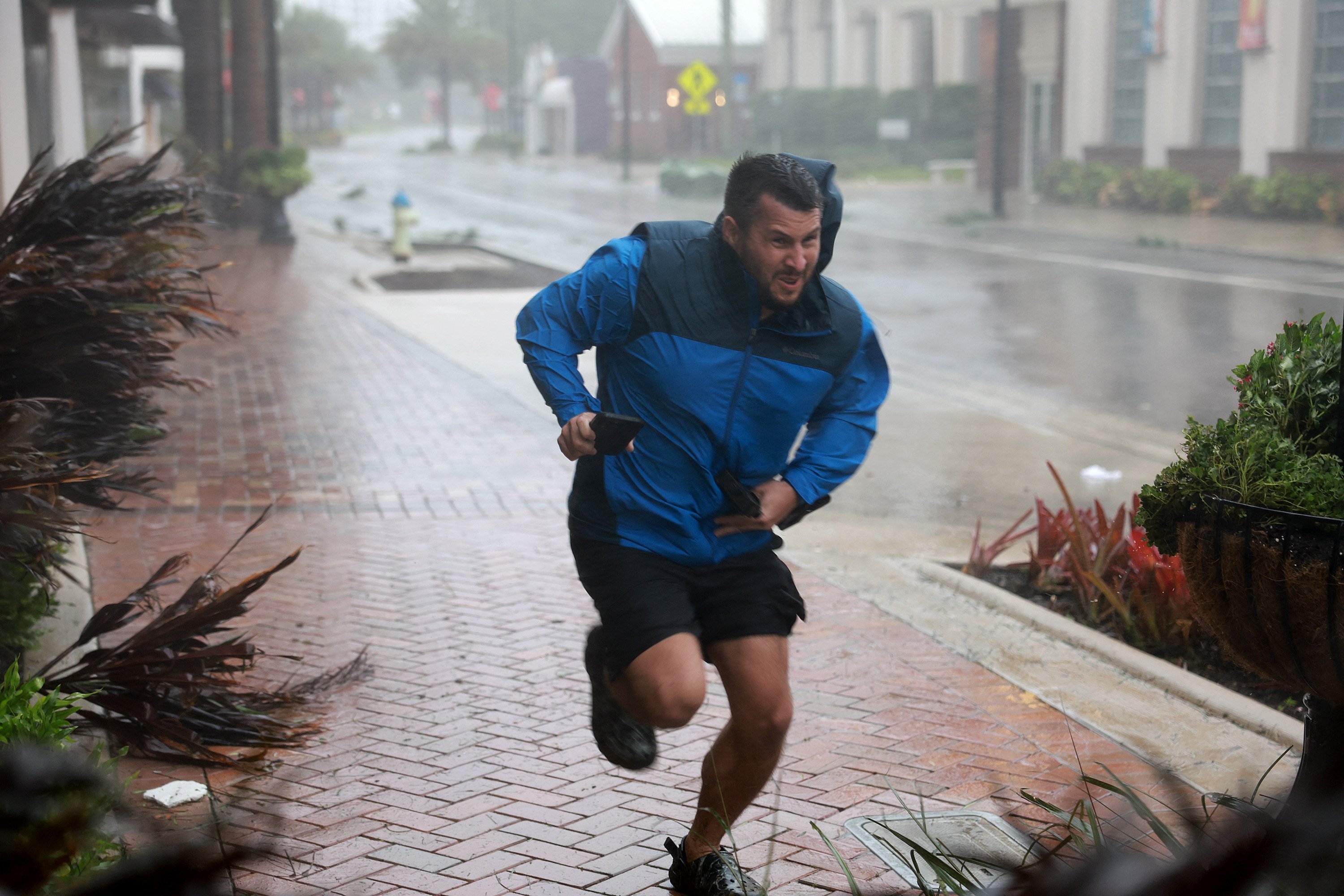 A man runs to a sheltered spot through the wind and rain from Hurricane Ian, Sarasota, Florida, U.S, Sept. 28, 2022. (AFP Photo)