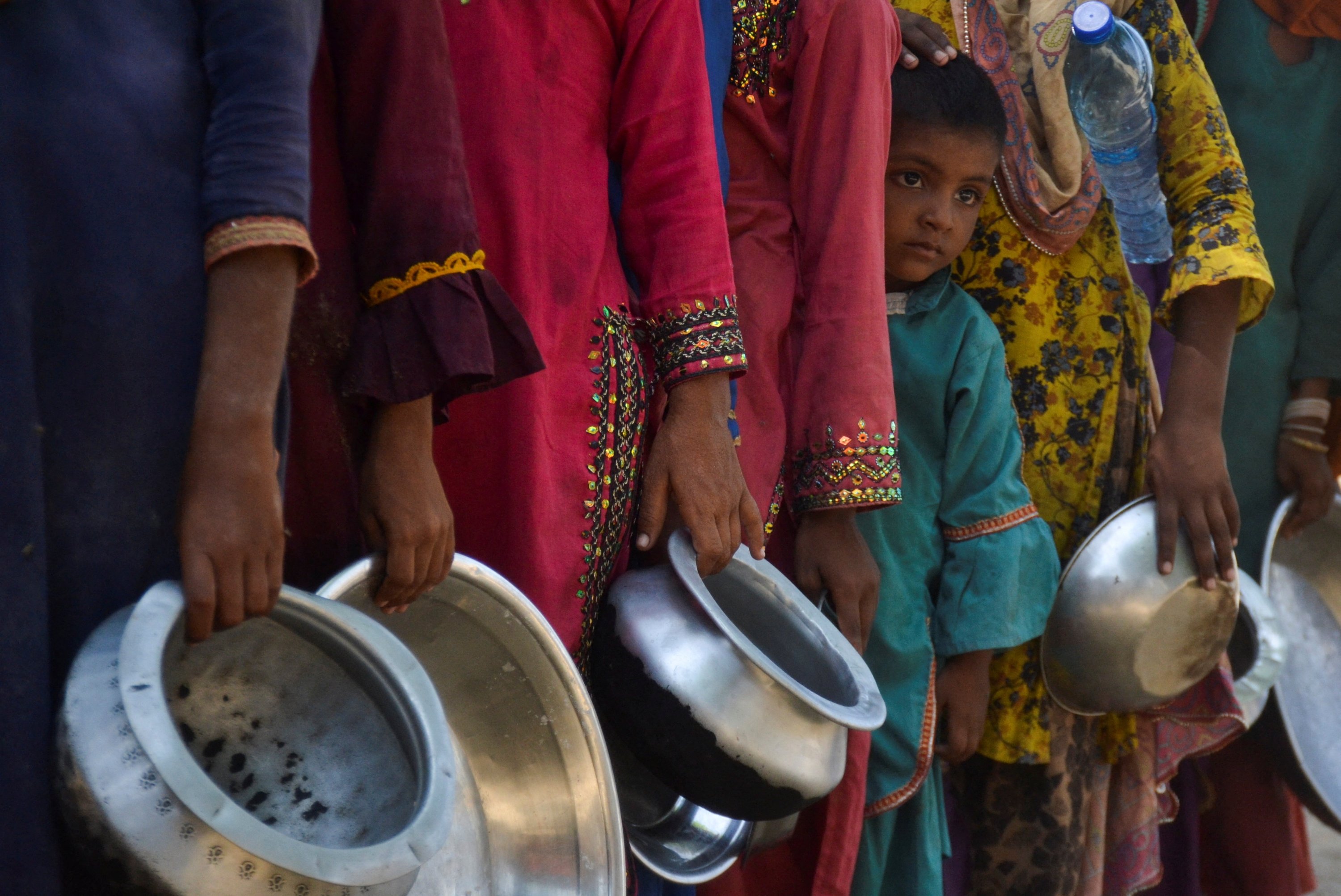 Orang-orang, yang mengungsi karena banjir, berkumpul untuk menerima bantuan makanan di sebuah kamp, ​​setelah hujan dan banjir selama musim hujan di Sehwan, Pakistan, 20 September 2022. (Foto Reuters)
