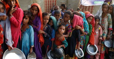 Flood victims gather to receive food handout in a camp, following rains and floods during the monsoon season in Sehwan, Pakistan, Sept. 14, 2022. (Reuters Photo)