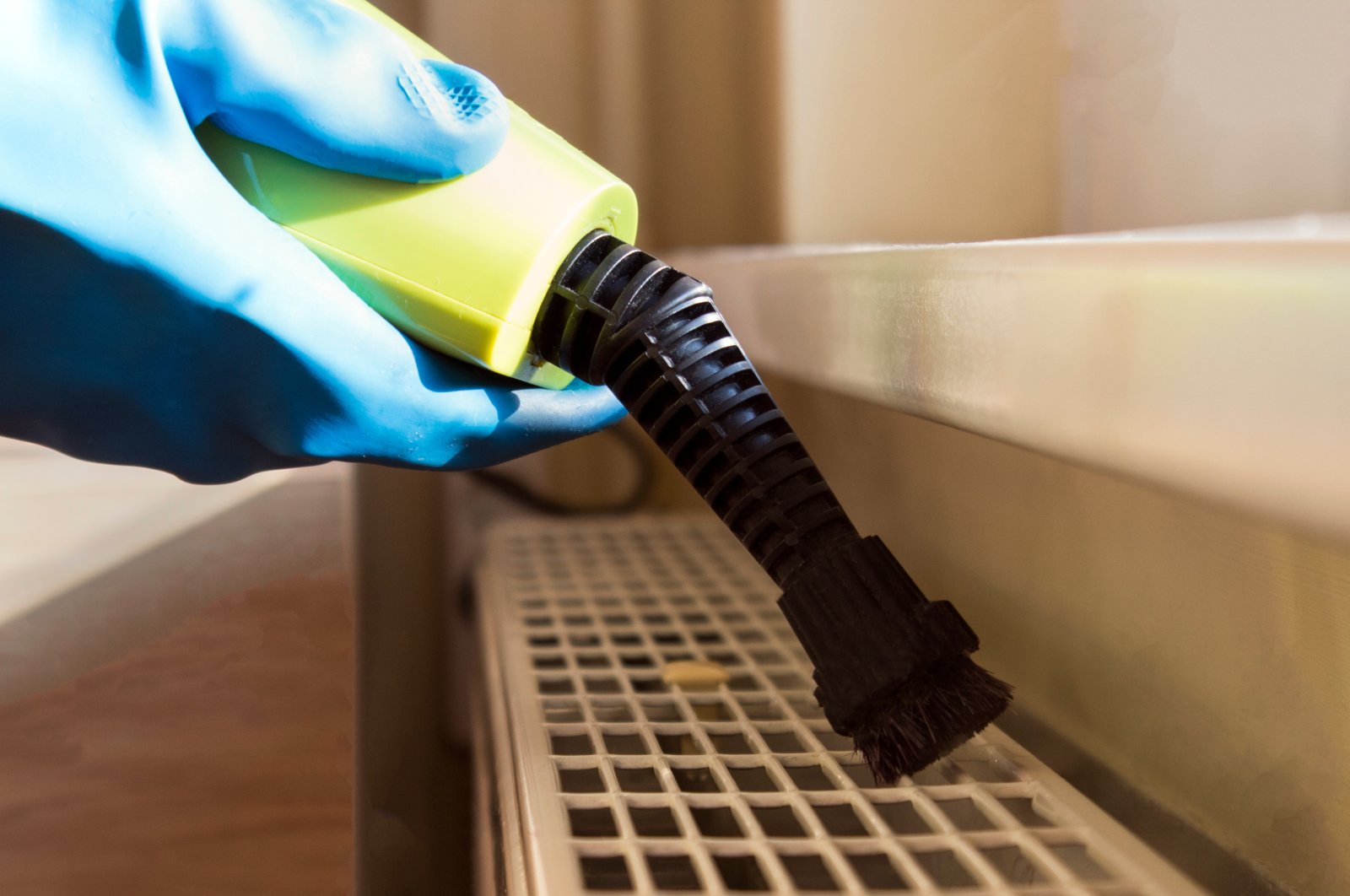 A professional steam cleans a radiator. (Shutterstock Photo)