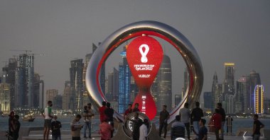 People gather around the official countdown clock showing the remaining time until the kickoff of the World Cup 2022, in Doha, Qatar, Nov. 25, 2021. (AP Photo)