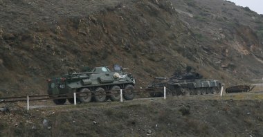 An armored personnel carrier of the Russian peacekeeping forces drives along a road past a burnt tank near Shusha in the region of Nagorno-Karabakh, Nov.13, 2020. (Reuters File Photo)