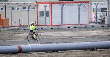 A worker rides a bike next to a pipeline at the landside construction site of the Uniper Liquefied Natural Gas (LNG) terminal at the Jade Bight in Wilhelmshaven on the North Sea coast, northwestern Germany, Sept. 29, 2022. (AFP Photo)