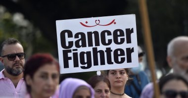 A Lebanese activist carries a placard "Cancer Fighter" during a march of solidarity with women diagnosed with breast cancer, in Beirut, Lebanon, Oct. 2, 2022. (EPA Photo)
