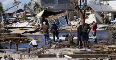 People stand on the destroyed bridge to Pine Island as they view the damage in the aftermath of Hurricane Ian, Spring Hill, Florida, U.S., Oct. 2, 2022. (AP Photo)