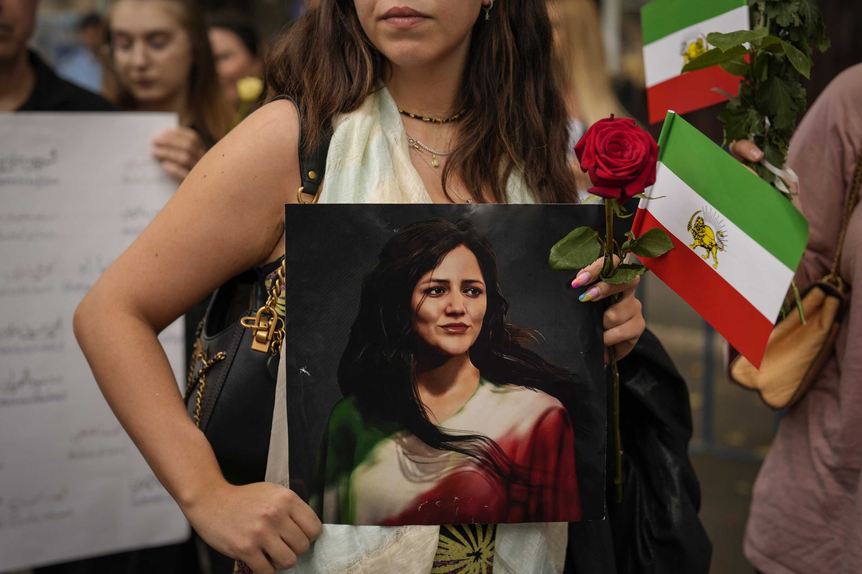 Seorang wanita memegang lukisan artistik Mahsa Amini, seorang wanita yang meninggal saat dalam tahanan polisi di Iran, selama protes terhadap kematiannya, di luar Kedutaan Besar Iran di Bucharest, Rumania, 1 Oktober 2022. (AP Photo)