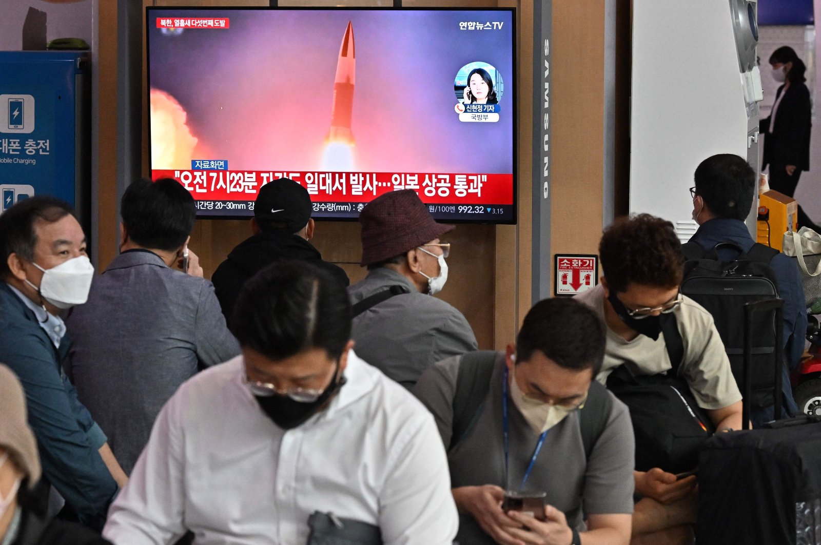 People watch a television screen showing a news broadcast of file footage of a North Korean missile test, at a railway station, Seoul, South Korea, Oct. 4, 2022. (AFP Photo)