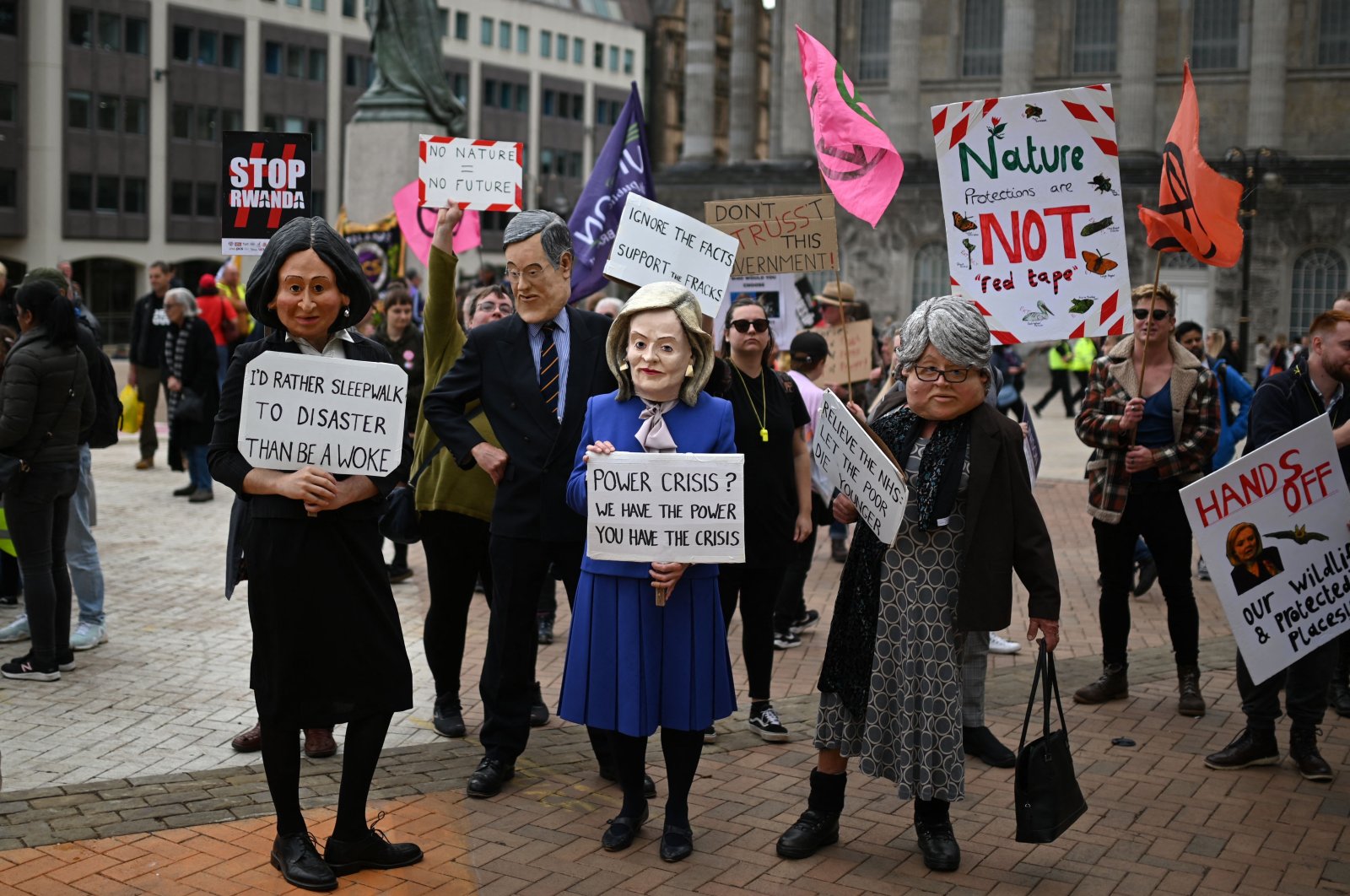 Protesters dressed like (L-R) Suella Braverman, Jacob Rees-Mogg, Liz Truss and Therese Coffey hold up placards at an anti-government protest in Victoria Square, Birmingham, central England, Oct. 2, 2022. (AFP Photo)