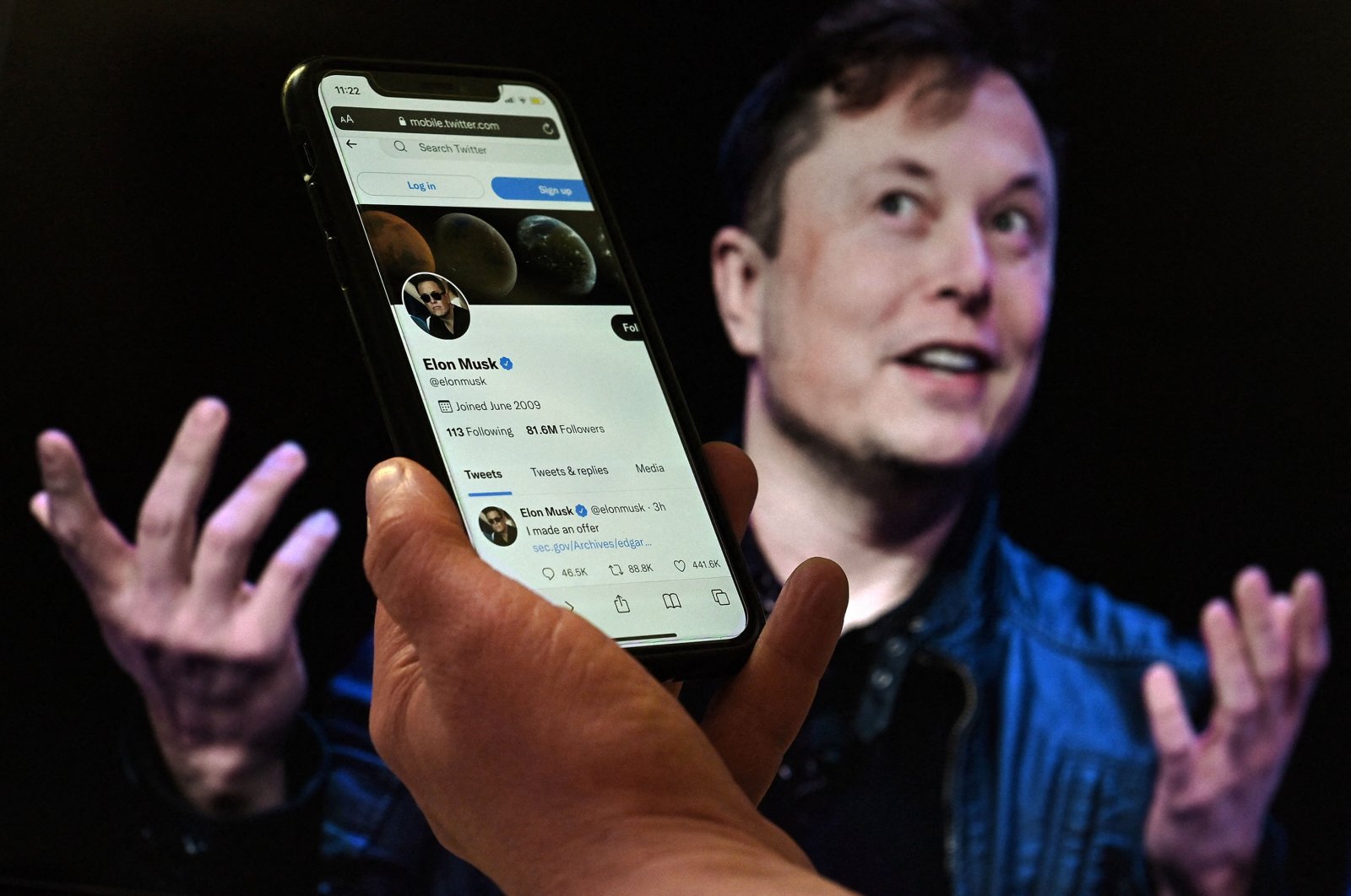 A phone screen displays the Twitter account of Elon Musk in front of a photo of him in the background in this illustration, Washington, D.C., U.S., April 14, 2022. (AFP Photo)