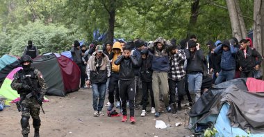 In this photo provided by the Serbian Ministry of Interior, Serbian Police officers escort migrants in Srpski Kustur, Serbia, Oct. 5, 2022. (AP Photo)
