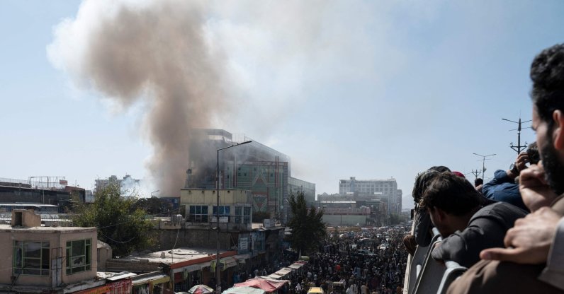 People watch smoke billowing from a fire at a business center mall in Kabul, Afghanistan, Oct. 5, 2022. (Photo by Wakil KOHSAR / AFP)
