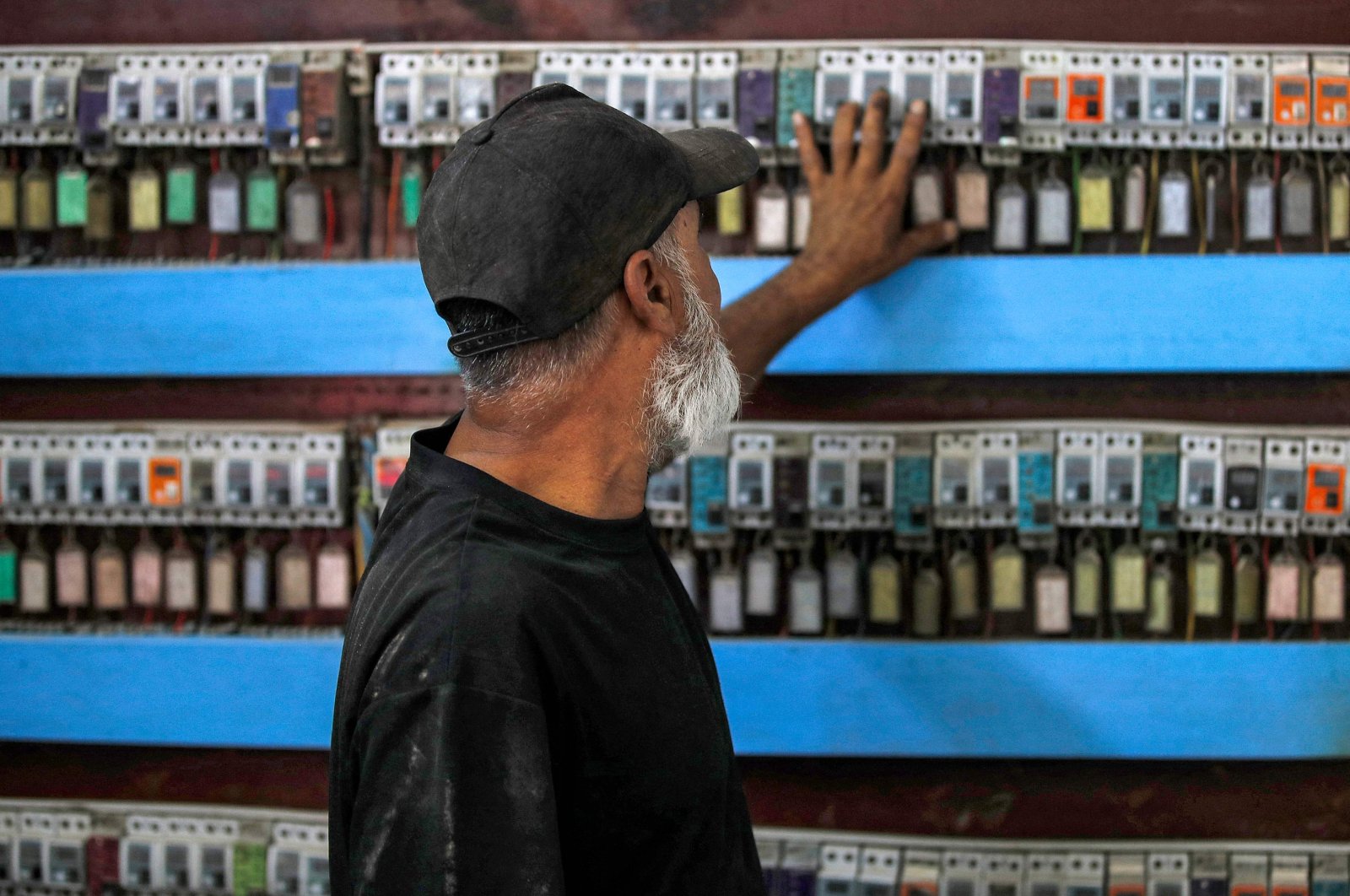 A technician monitors the switches of clients subscribing for electrical power delivery to a battery of fuel-based electricity generators in the eastern Sadr City suburb of Baghdad, Iraq, Sept. 27, 2022. (AFP Photo)