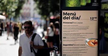 A pedestrian walks past a board showing today's menu in Madrid, Spain, Sept. 5, 2022. (AFP Photo)