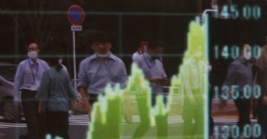 Pedestrians are reflected on a board displaying a graph of the Japanese yen exchange rate against the U.S. dollar outside a brokerage in Tokyo, Japan, Sept. 22, 2022. (Reuters Photo)