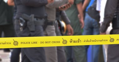 Yellow police tape says "Police line do not cross," in Thai. (Shutterstock Photo)