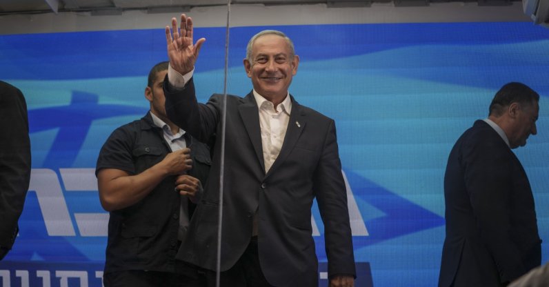 Former Israeli Prime Minister Benjamin Netanyahu waves after delivering an election campaign speech from inside a modified delivery truck with a side wall replaced with bulletproof glass. Beersheba, Israel, Sept. 13, 2022. (AP Photo)