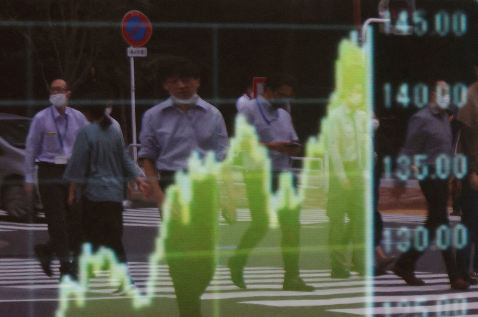 Pedestrians are reflected on a board displaying a graph of the Japanese yen exchange rate against the U.S. dollar outside a brokerage in Tokyo, Japan, Sept. 22, 2022. (Reuters Photo)
