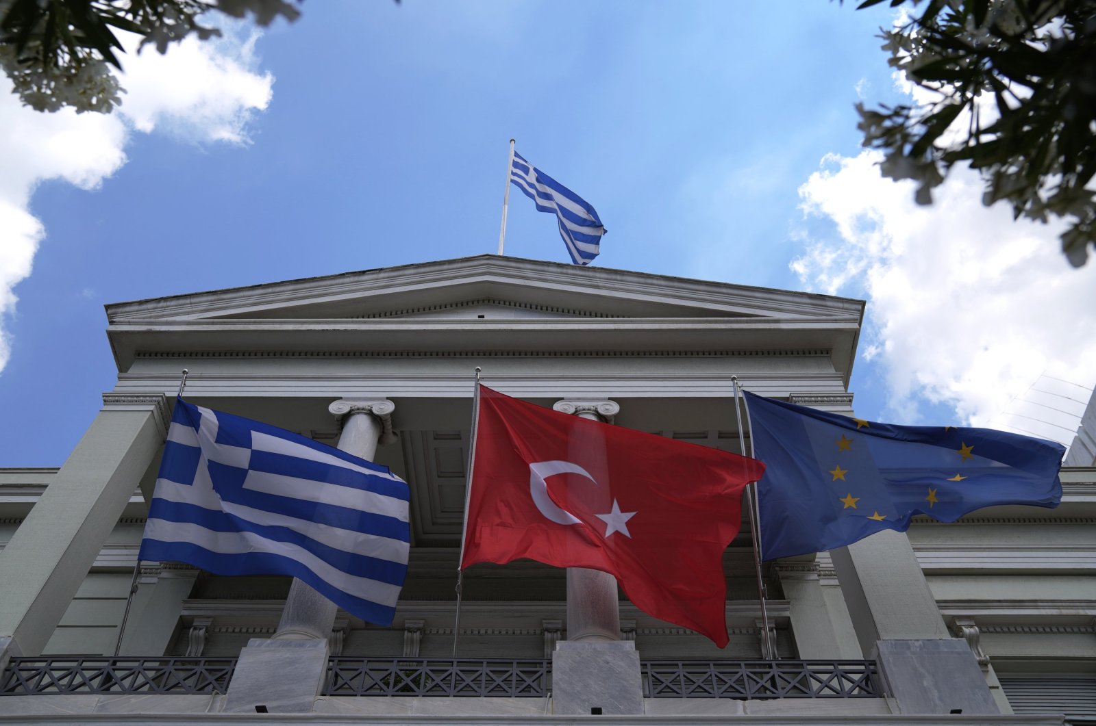 Turkish (C), Greek (L) and European Union flags wave on the Greek Foreign Ministry building, May 31, 2021. (AP File Photo)