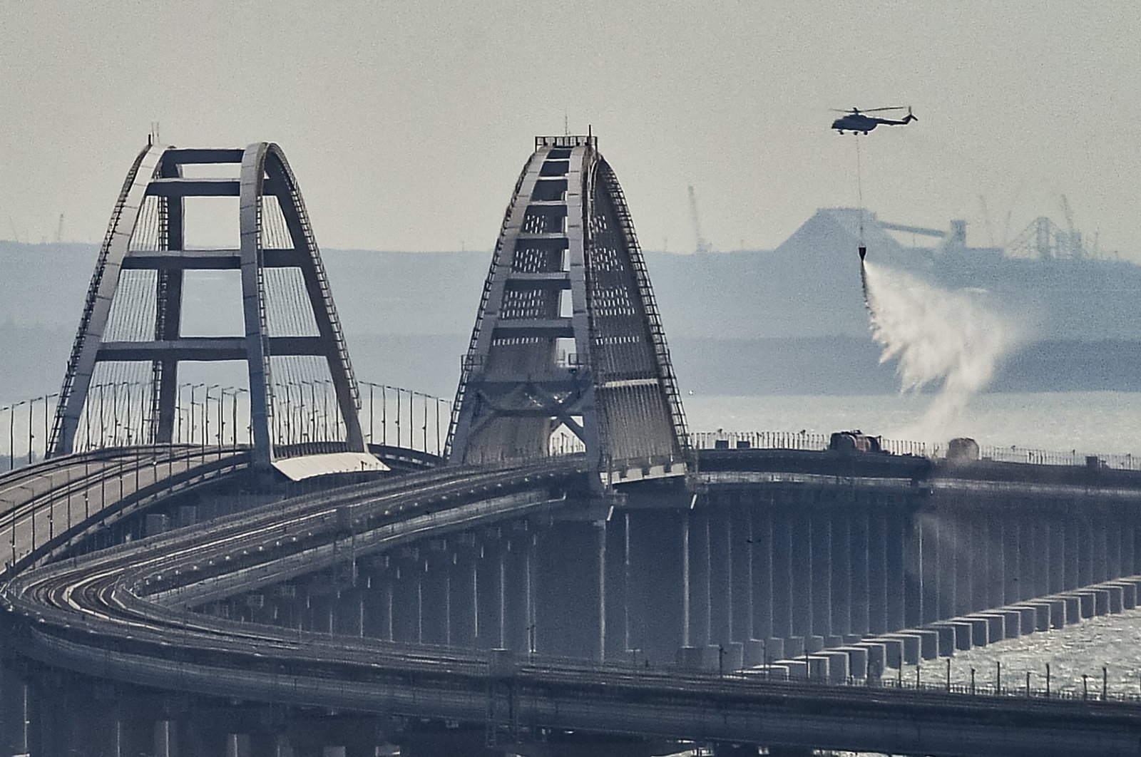 A firefighter helicopter pours water on the fire on a collapsed part of the Kerch Strait bridge in Crimea, Oct. 8, 2022. (EPA Photo)