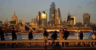 People cross Waterloo Bridge during the evening rush hour with skyscrapers of the City of London financial district seen behind in London, Britain, Oct. 10, 2022. (Reuters Photo)