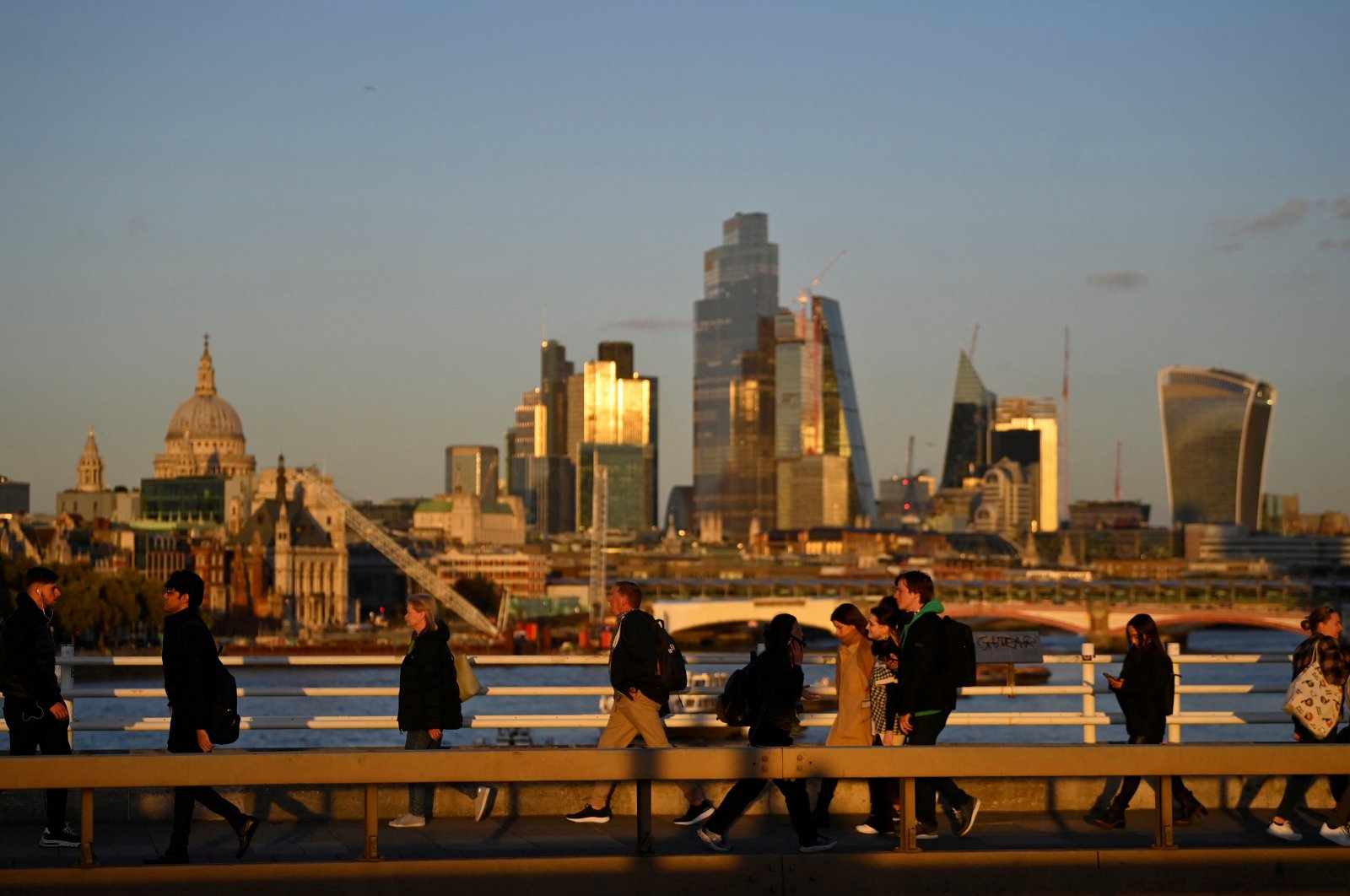 People cross Waterloo Bridge during the evening rush hour with skyscrapers of the City of London financial district seen behind in London, Britain, Oct. 10, 2022. (Reuters Photo)