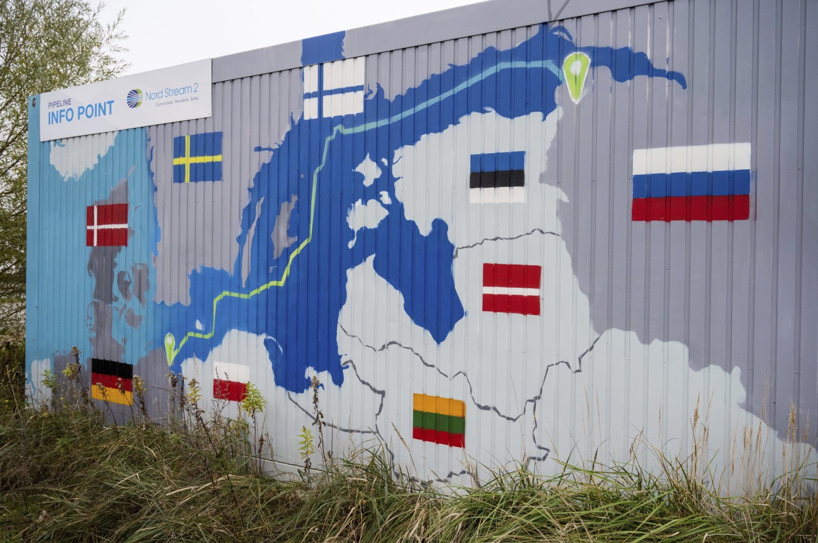 A sign reading &quot;Nord Stream 2 Committed. Reliable. Safe.&quot; hangs above a painted map of the Nord Stream 2 pipeline from Russia to Germany at the natural gas receiving station in Lubmin, Germany, Nov. 16, 2021. (AP Photo)