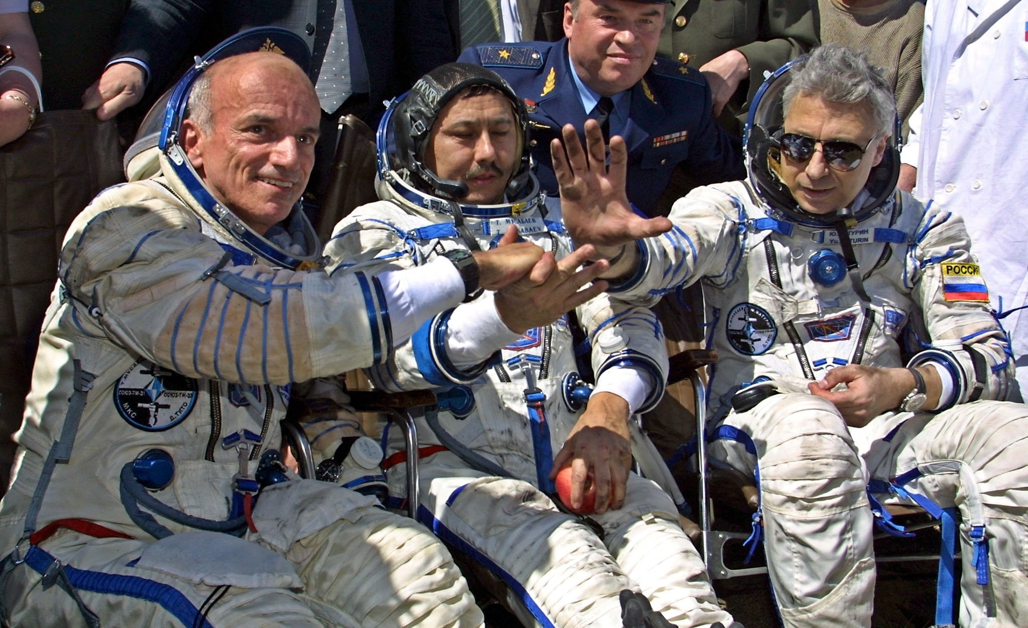 U.S. space tourist Dennis Tito (L) shakes hands with his crew members Talgat Musabayev (C) and Yuri Baturin (R) after their landing near the Kazakh town of Arkalyk, May 6, 2001. (Photo by Alexander NEMENOV / AFP)