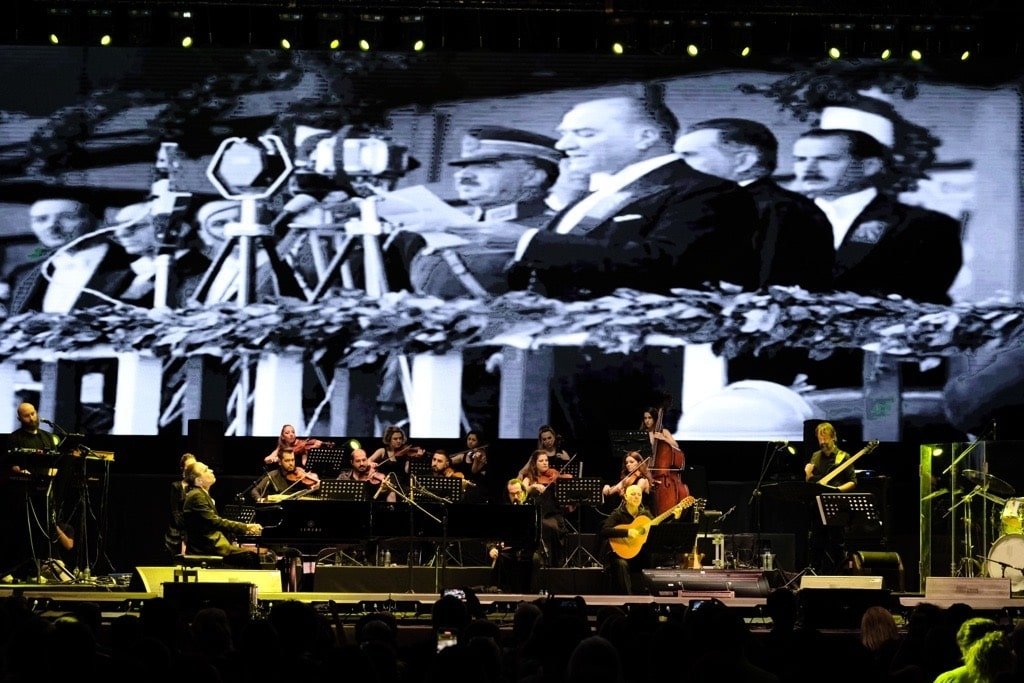 Fahir Atakoğlu selama penampilannya dengan film dokumenter yang diputar di atas panggung.  (Foto milik organisasi)