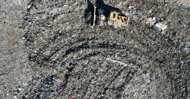 An aerial view shows a digger pushing waste to flatten a hill of rubbish, at a private landfill in Viggianello, on the French Mediterranean island of Corsica, Oct. 5, 2022. (AFP Photo)