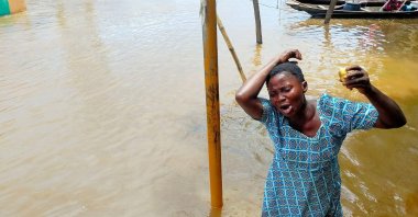 In this photo released by National Emergency Management Agency, a woman cries as she stand on a flooded street following a boat accident, Anambra, Nigeria, Oct. 7, 2022. (NEMA via AP)