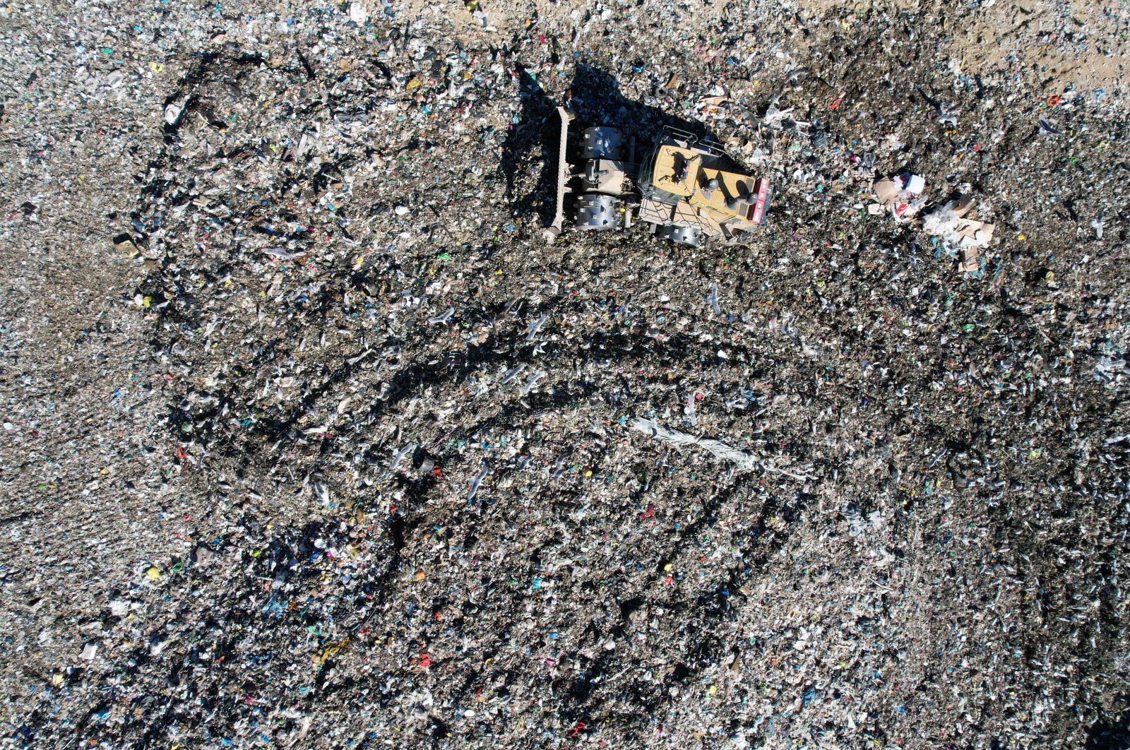 An aerial view shows a digger pushing waste to flatten a hill of rubbish, at a private landfill in Viggianello, on the French Mediterranean island of Corsica, Oct. 5, 2022. (AFP Photo)